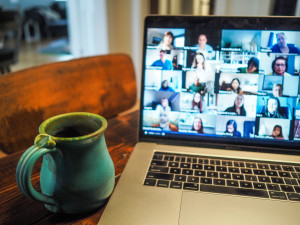 Teetasse vor einem Laptop, auf dem eine Videokonferenz läuft